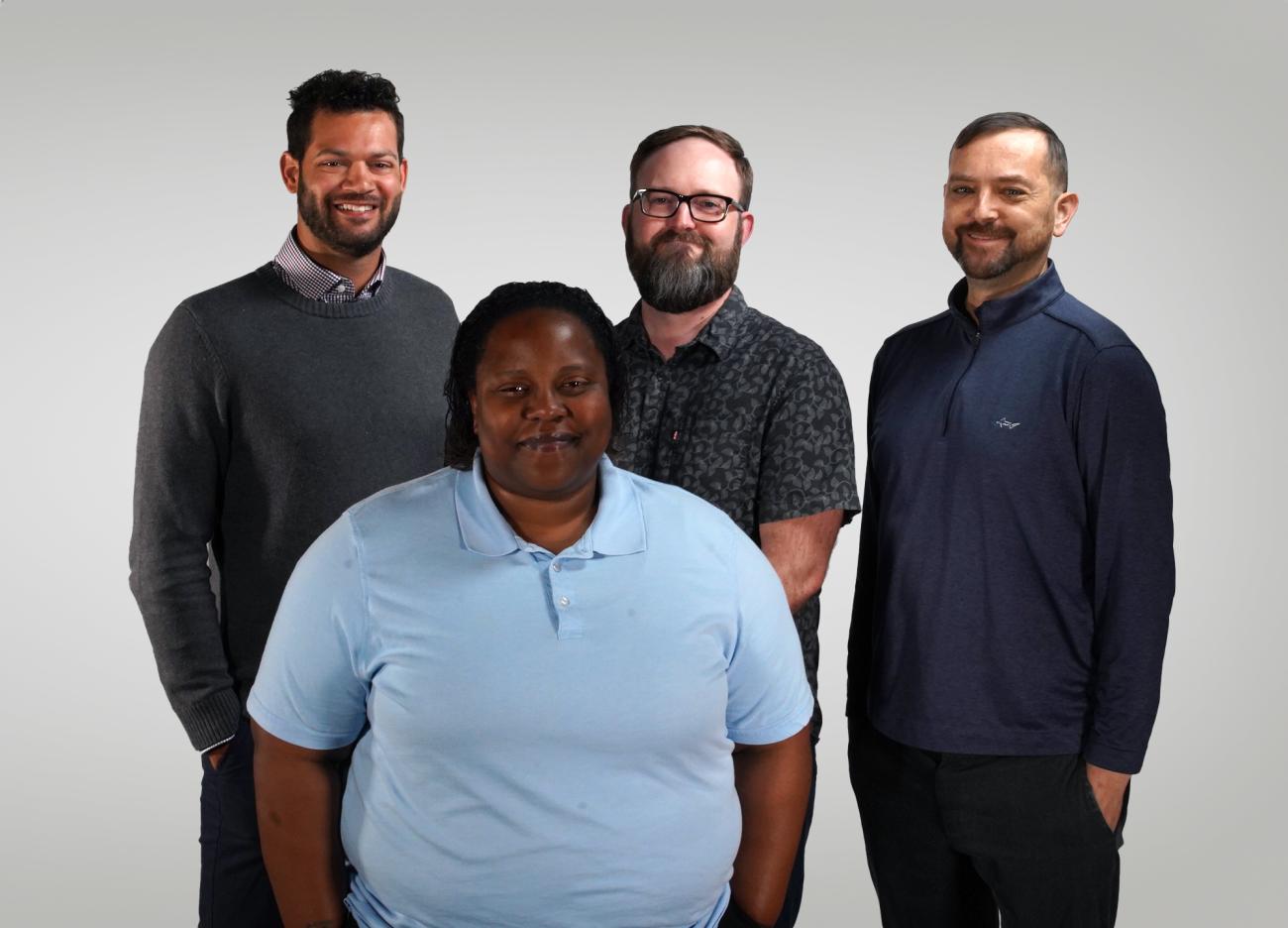 4 members of the Civil Rights and Title IX staff smile for the camera in front of a white backdrop.